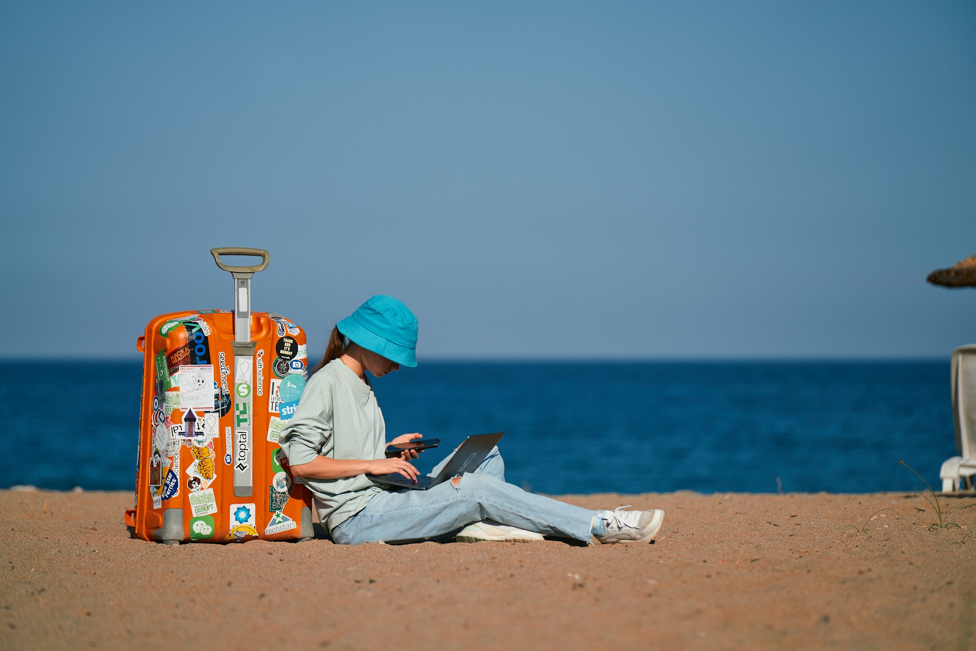Guide to Building Reliable Finances While Living the Digital Nomad Life Digital Nomad sitting on the beach with a suitcase